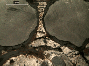 Stereo-optical micrograph of polished cross sectioned core showing corrosion and corrosion induced cracking of steel rebar.